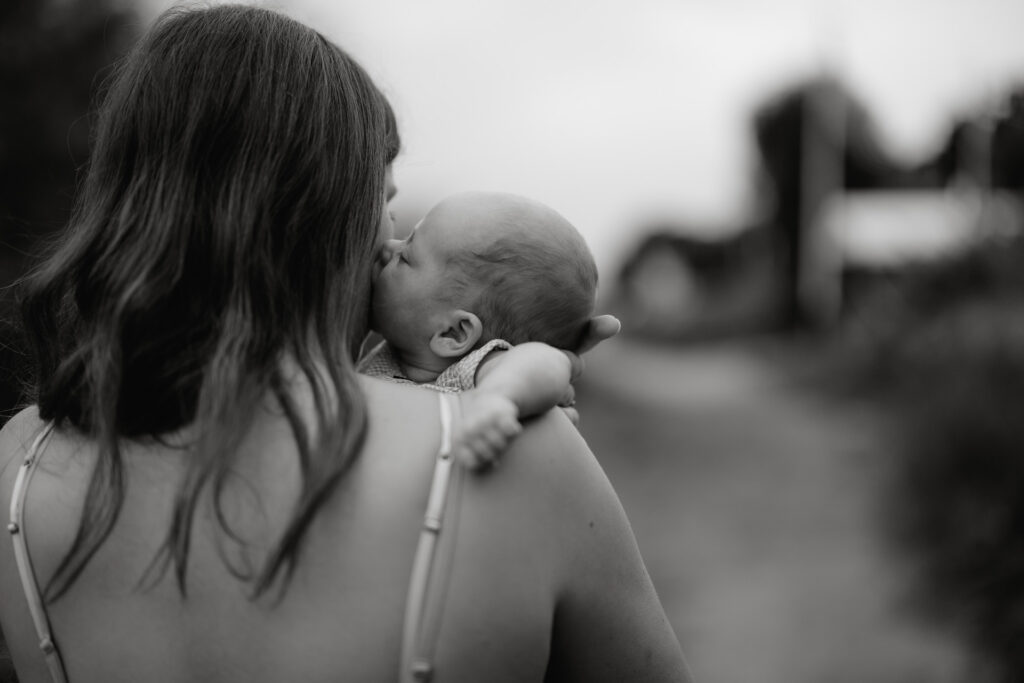 Familienfotografie Hamburg. Eine Mutter mit ihrem Neugeborenen, dass sie küsst.