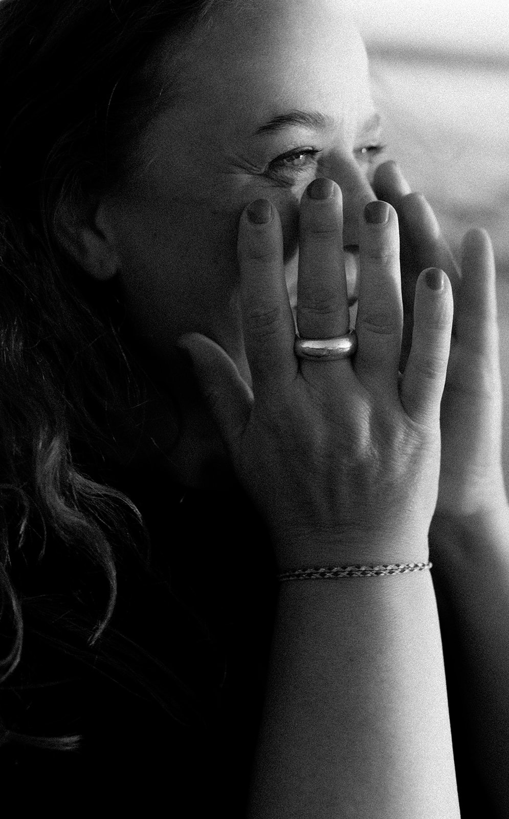 Angie Hagedorn, Hochzeitsfotografin, lehnt sich lächelnd an eine dunkelblaue Hausfassade und hält eine Kamera in der Hand.